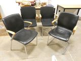 four black leather office chairs with chrome legs in a room