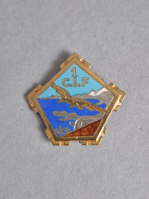une broche dorée et bleue sur laquelle est représenté un oiseau