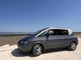 a small gray van parked on the beach by the water