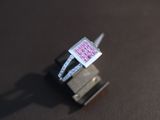 a pink diamond ring sitting on top of a black surface
