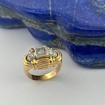 an image of a gold and diamond ring sitting on top of a blue stone