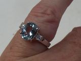 la main d'une femme tenant une bague sertie d'une pierre bleue