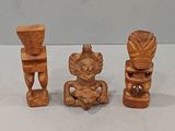 three carved wooden figurines sitting on top of a white surface