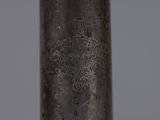close up of a metal pipe with writing on it on a gray background