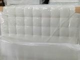 Des cartons contenant des matelas sont empilés les uns sur les autres dans un entrepôt