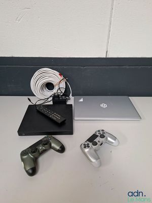 une table sur laquelle se trouvent un ordinateur portable, une manette de jeu et d'autres objets