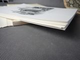 a stack of papers sitting on a table with a chair in the background