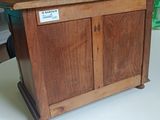 a small wooden cabinet on a table with a sign on it