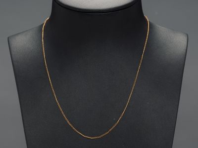 a gold necklace on a mannequin neck with a black background
