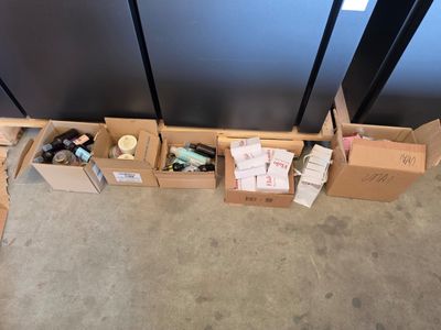 Plusieurs cartons contenant des objets divers sont alignés sur le sol.