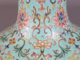 a hand holding a blue vase with a floral design on it