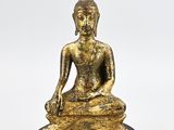 a gold statue of a seated buddha on a wooden base