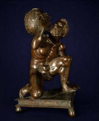 statue en bronze représentant un garçon tenant un ballon, posée sur un socle en bois