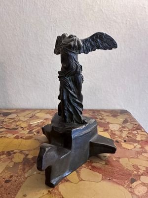 statue d'une femme tenant un oiseau, posée sur un socle posé sur une table en marbre