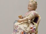 a figurine of a woman sitting on a chair