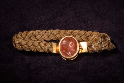 a close up of a rope bracelet with a red stone in the center