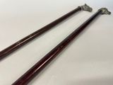 pair of antique wooden canes with metal handles on a white surface