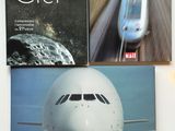trois livres posés sur une table, avec un avion et un train en arrière-plan