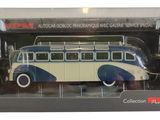 un petit bus en jouet dans une boîte, sur fond blanc, orné d'une bande rouge et bleue