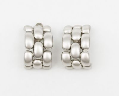 two pairs of silver earrings on a white surface with a white background