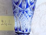 un vase en verre bleu posé sur une table, sur lequel est posée une note