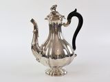 une théière ancienne en argent, avec une anse noire sur fond blanc