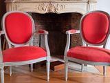 two red chairs sitting next to each other in front of a fireplace