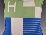 un oreiller vert et bleu sur lequel figure un « h » blanc