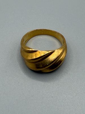 une image représentant une bague en or posée sur une surface grise