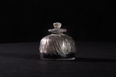 a small glass bottle with a silver lid sitting on a black surface