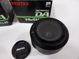 a camera lens sitting next to a box of penstax