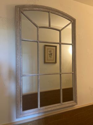 un miroir sur le mur au-dessus d'un lavabo dans une salle de bains