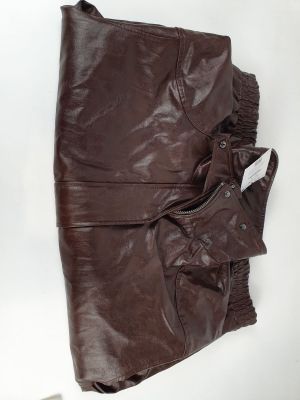 une veste et un pantalon en cuir marron posés sur une surface blanche