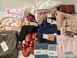 a pile of clothes and shoes on a bed
