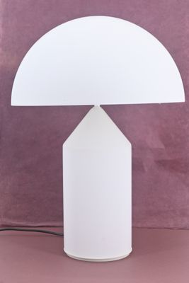 a white lamp on a table with a pink background