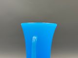 a blue vase sitting on a table with a gray background
