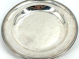 an antique silver plate on a white background with a brown handle