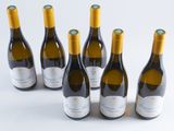 six bottles of wine are lined up in a row on a white surface