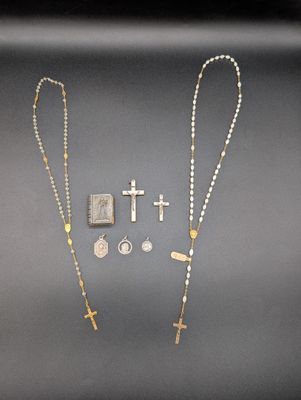 un gros plan sur un chapelet, une croix et d'autres objets posés sur une table