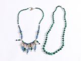 a close up of two necklaces on a white surface