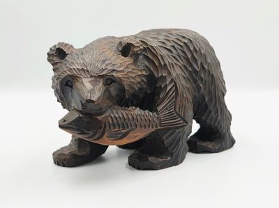 une statue représentant un ours tenant un poisson dans sa gueule