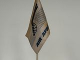 un petit drapeau posé sur un support, sur une surface blanche