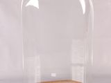un dôme en verre transparent reposant sur un socle en bois, sur fond blanc