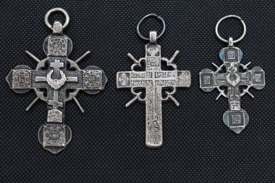 three silver crosses on a black background, one with a cross and the other with a cross on it