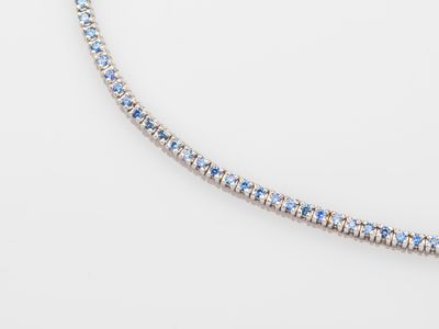 a blue and white diamond tennis necklace on a white surface