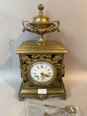 a gold clock sitting on a table next to a silver spoon