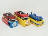 trois petites voitures sont posées sur des boîtes sur une surface blanche