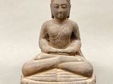 statue of a seated buddha on a rock with a white background