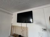 a flat screen tv mounted on the wall above a microwave