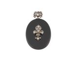 un gros plan d'une broche ovale noire ornée d'une fleur